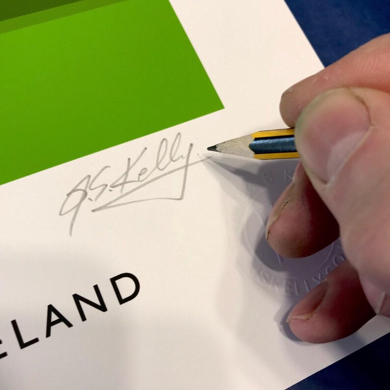 A hand is signing a document with a pencil, and the document appears to be a green and white background with the word "LAND" written on it.