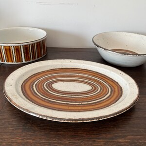 May include: A white ceramic oval platter with brown concentric circles. The platter has a slightly raised rim.