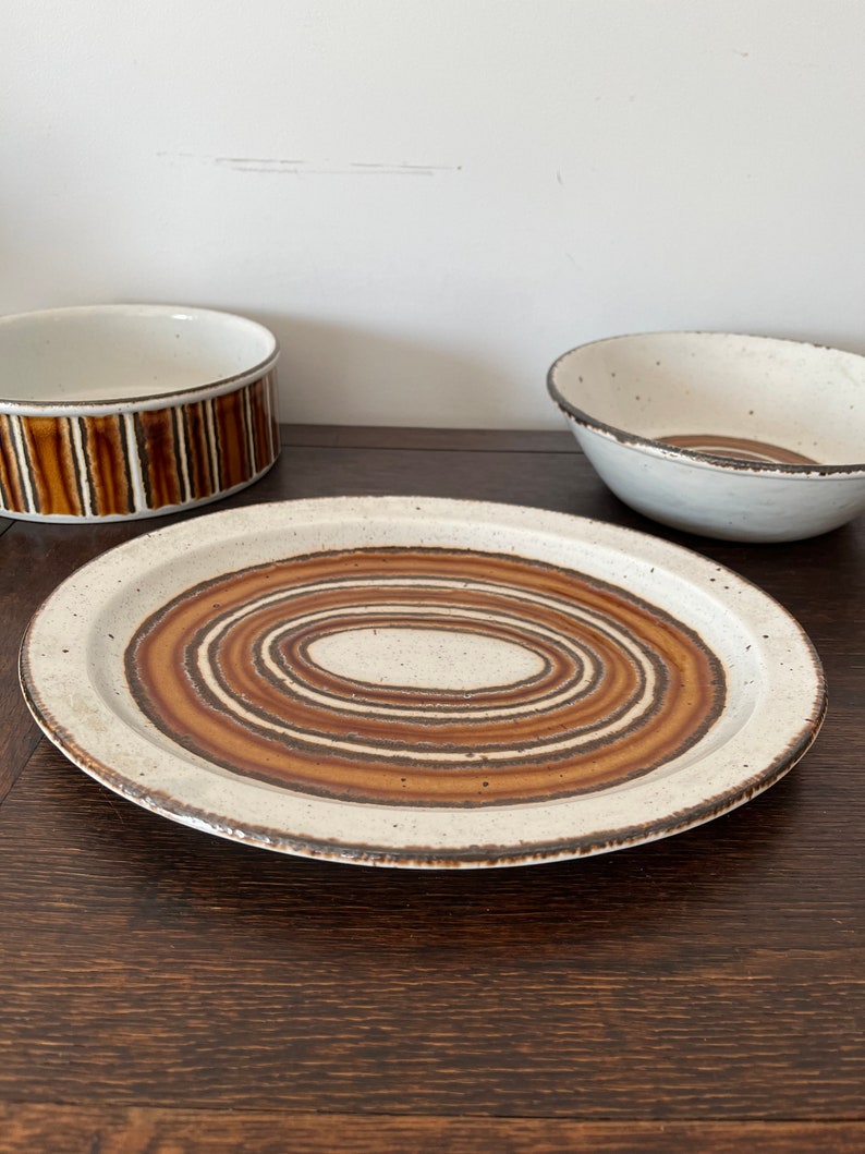 May include: A white ceramic oval platter with brown concentric circles. The platter has a slightly raised rim.