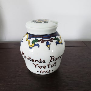 Puede incluir: Tarro de mostaza de cerámica blanca con un diseño floral azul y verde y el texto "Moutarde Bocquet Yve tot -1735-"