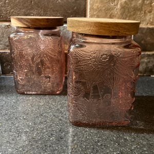 2 pots en verre rose, couvercle en bois, motifs de fleurs gravés,