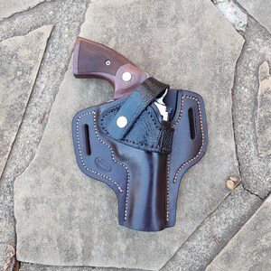 May include: A brown leather holster with a black alligator pattern and a brown gun inside.