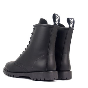 May include: Black leather combat boots with a lace-up design and a thick, lugged sole. The boots have a pull tab at the back with the word "ADIX" in white. The boots are shown from the side and back against a white background.