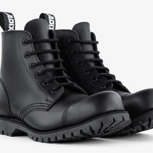 Puede incluir: Un par de botas de combate de cuero negro con dise&ntilde;o de cordones y suela gruesa con tacos. Las botas tienen punta redondeada y una leng&uuml;eta en la parte trasera con la palabra "ADIX" impresa.