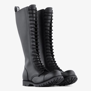 May include: Pair of black knee-high boots with a lace-up design. The boots have a rounded toe, a thick sole, and a pull tab at the top. The boots are made of a smooth, matte material.