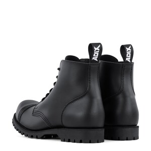 Puede incluir: Botas de combate de cuero negro con punta redondeada y suela gruesa con tacos. Las botas tienen un dise&ntilde;o con cordones y una leng&uuml;eta en la parte trasera con la palabra "ADIX" en blanco. Duraderas y elegantes.