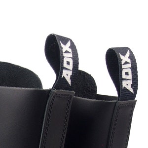 May include: Close-up of black leather boots with pull tabs. The pull tabs are black with the white text "ADIX". The boots have a smooth, shiny finish and are likely made of leather.
