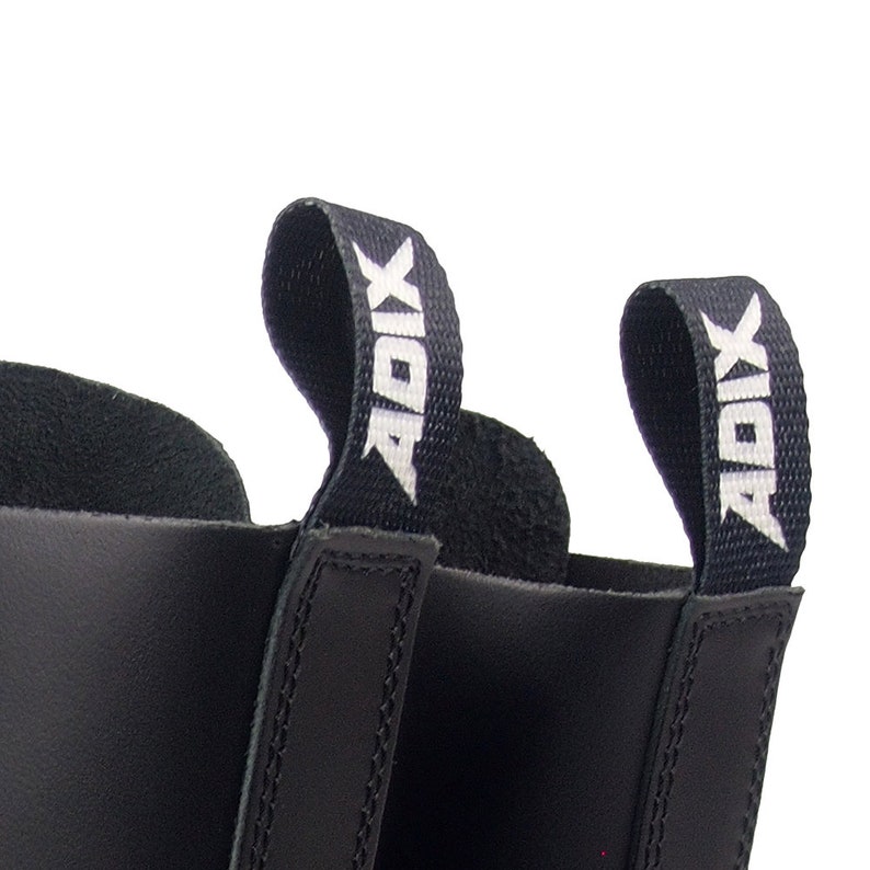 May include: Close-up of black leather boots with pull tabs. The pull tabs are black with the white text "ADIX". The boots have a smooth, shiny finish and are likely made of leather.