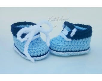 Könnte beinhalten: Ein Paar Babyschuhe in hellblau mit weißen Schnürsenkeln und einem dunkelblauen Besatz. Die Schuhe sind gehäkelt und haben einen lässigen Stil.