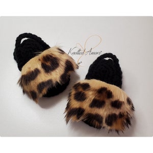 May include: A pair of black crocheted baby booties with a leopard print fur trim. The booties are handmade and have a soft, cozy feel.
