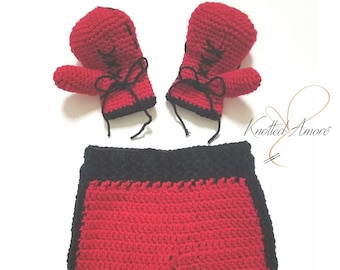 May include: Red and black crocheted boxing gloves and shorts. The gloves have black laces and a black trim. The shorts have a black waistband and black trim on the sides.