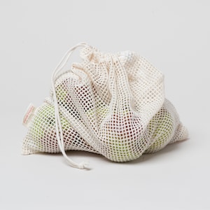 May include: A white mesh produce bag with a drawstring closure, filled with green apples. The bag has a red label that says "Planet Friendly".