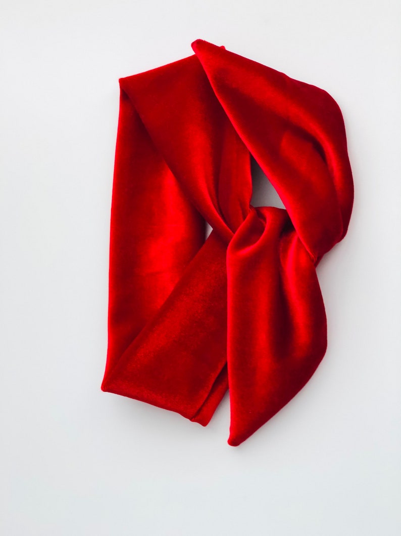May include: A red velvet headband with a knotted design. The headband is made of soft, plush velvet and is perfect for adding a touch of elegance to any outfit.