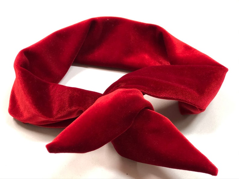 May include: A red velvet headband with a knotted design. The headband is made of soft, plush velvet and is perfect for adding a touch of elegance to any outfit.
