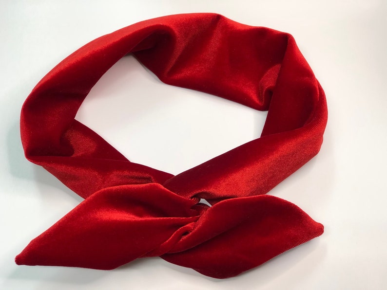 May include: A red velvet headband tied in a knot. The headband is made of soft, plush velvet and is perfect for adding a touch of elegance to any outfit.