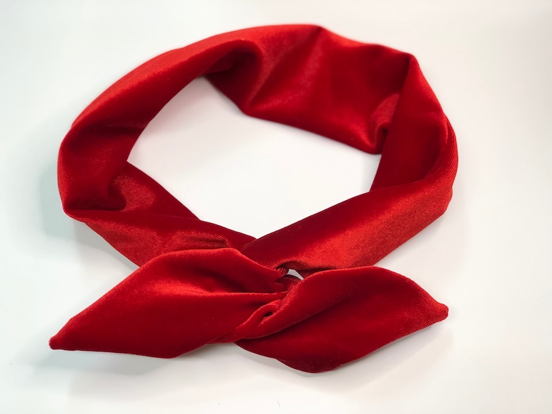 May include: A red velvet headband with a knotted bow. The headband is made of soft, plush velvet and is perfect for adding a touch of elegance to any outfit.