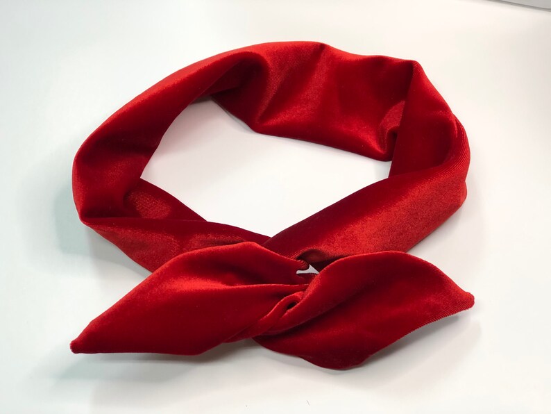 May include: A red velvet headband tied in a knot. The headband is made of soft, plush velvet and is perfect for adding a touch of elegance to any outfit.
