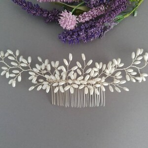 May include: A silver hair comb with a delicate design of pearl-like beads arranged in a vine-like pattern.