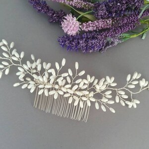 May include: A silver hair comb with a delicate design of white pearl beads arranged in a branch-like pattern.
