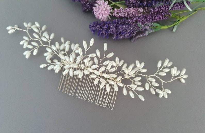 May include: A silver hair comb with a delicate design of white pearl beads arranged in a floral pattern.