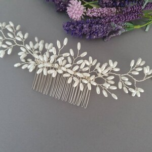May include: A silver hair comb with a delicate design of pearl-like beads arranged in a vine-like pattern.