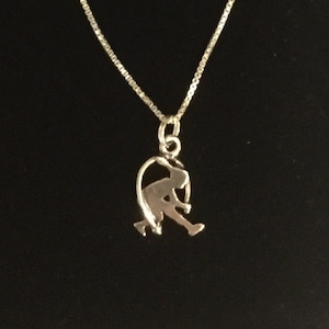 May include: A silver necklace with a pendant shaped like a person running. The pendant is a cutout design, so the person is visible against the background.