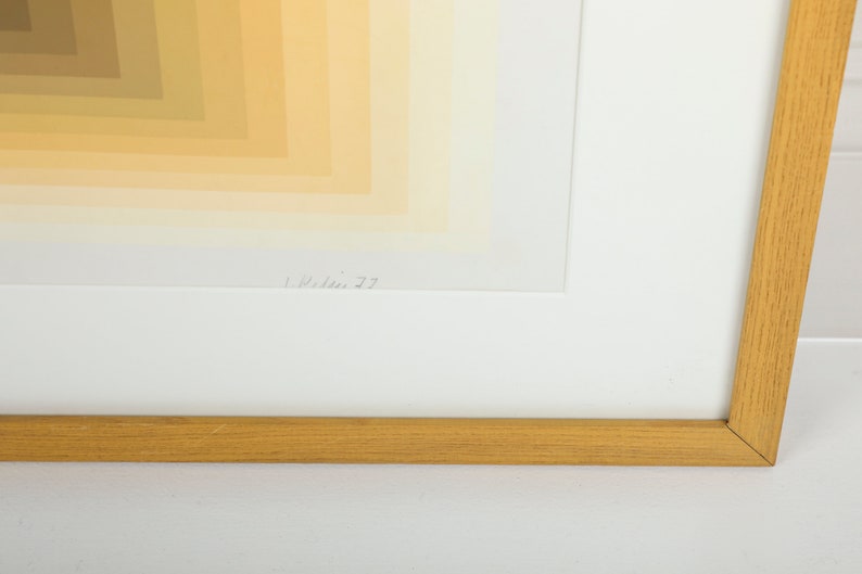 May include: A framed abstract print with a geometric pattern of yellow, orange, and brown hues. The print is signed "L. Wilson 77" in the bottom right corner.