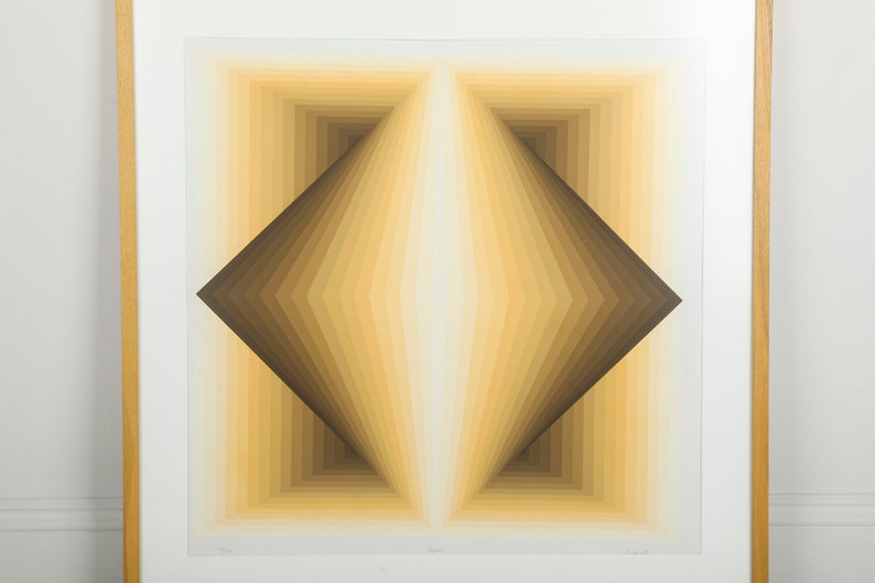 May include: A framed abstract print with a geometric design in shades of brown and yellow. The print features a series of concentric squares and triangles that create a sense of depth and perspective.