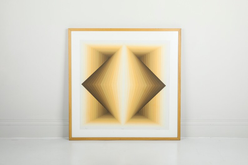 May include: A framed abstract geometric print with a diamond shape in shades of brown, yellow, and white.