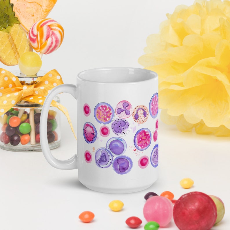 May include: White ceramic mug with a colorful design of purple, pink, and orange watercolor circles. The circles have a pattern of cells inside them.
