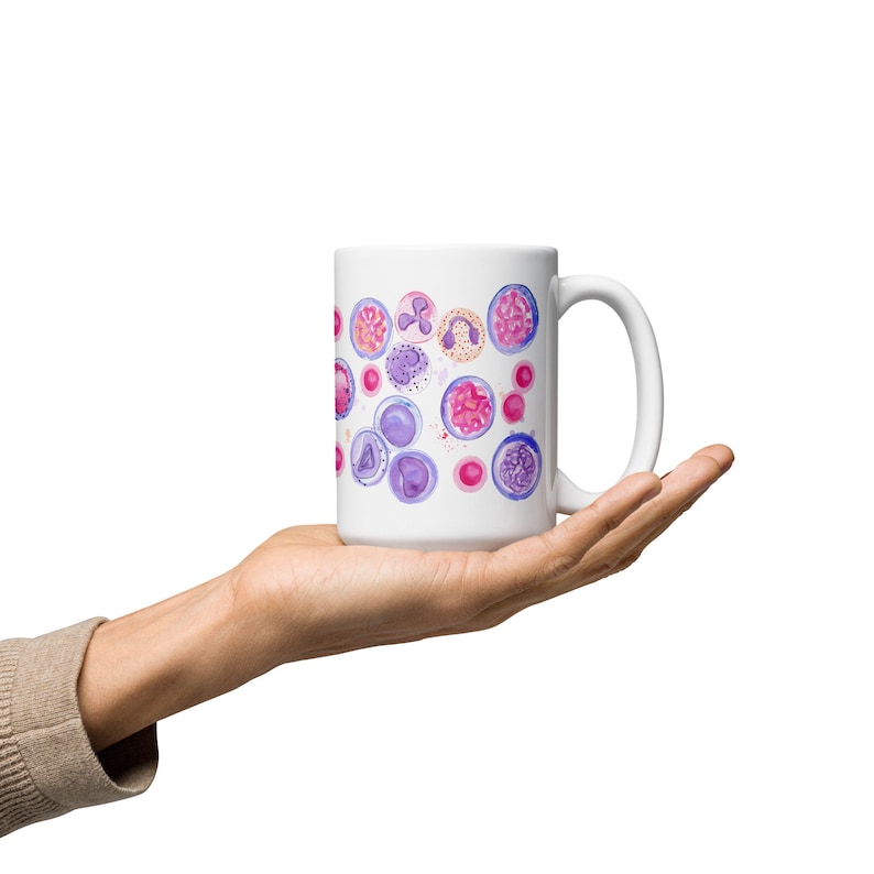 May include: White ceramic mug with a colorful watercolor design of purple and pink cells. The mug has a white handle.