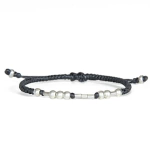 May include: A black braided cord bracelet with silver beads and a silver bar accent.