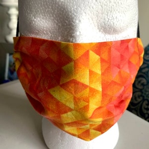 May include: A reusable face mask with a geometric pattern in shades of orange and yellow.