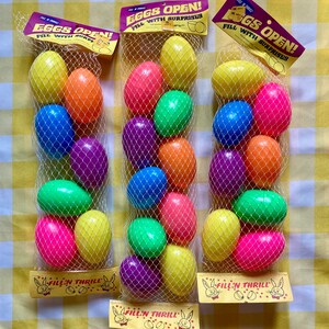 Peut inclure: Trois sacs d'œufs de Pâques en plastique, chacun contenant 12 œufs colorés. Les sacs sont étiquetés "Eggs Open! Fill with Surprises" et "Fill'n Thrill".