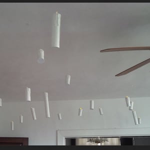 May include: A white ceiling with a ceiling fan and multiple white candles hanging from the ceiling.