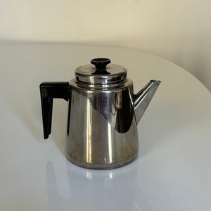 May include: A silver stainless steel teapot with a black plastic handle and a black knob on the lid.