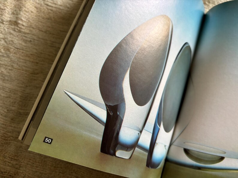 May include: Abstract image of a pair of high-heeled shoes with a futuristic design. The shoes are primarily silver and white, with a sleek, aerodynamic shape. The image is from a magazine.
