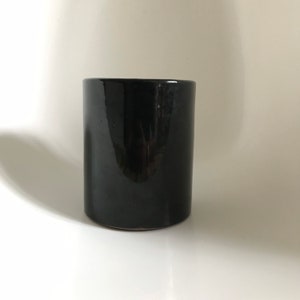 以下が含まれることがあります： 光沢のある仕上げの黒いセラミック製の円筒形の花瓶