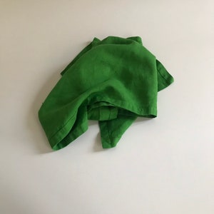 Puede incluir: Una toalla de cocina de lino verde doblada sobre una superficie blanca.