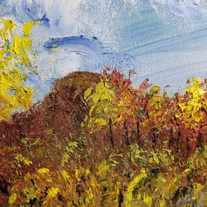 May include: A painting of a landscape with a brown hill in the background and a field of yellow and red flowers in the foreground. The sky is blue with white clouds.