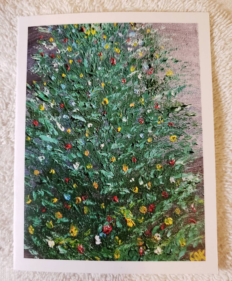 May include: A greeting card with an impressionistic painting of a Christmas tree. The tree is painted in shades of green with small, colourful dabs of red, yellow, and white, suggesting decorations. The background is a soft, muted purple.