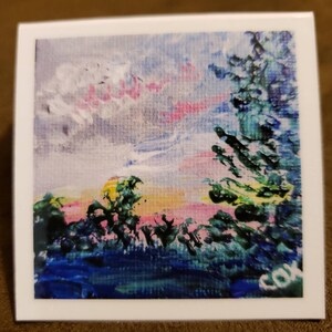 May include: A painting of a sunset over a forest with a pink and yellow sky. The trees are green and blue, and there is a white cloud in the sky. The painting is signed "COX" in the bottom right corner.
