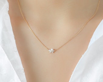 May include: A delicate gold chain necklace with a small, sparkling flower pendant featuring a pearl center.