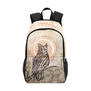 May include: A brown and black owl with a mandala design behind it. The owl is perched on a branch with a vintage, distressed background. The backpack is black with a zipped pocket.
