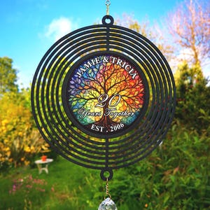 May include: A black metal wind spinner with a circular design. The centre has a colourful tree image and the text "JAMIE & TRICIA 20 Years Together EST. 2006". A crystal ball hangs below.