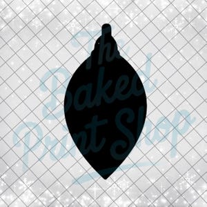 May include: A black teardrop-shaped Christmas ornament silhouette. The ornament has a small loop at the top for hanging. The background is a white grid pattern with scattered snowflakes, and the text "The Baked Print Shop" is visible.