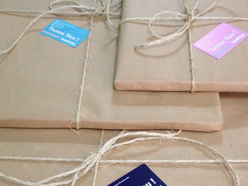 May include: Three packages wrapped in brown paper with twine and tied with a bow. Each package has a small card attached with the text "Thank You!" printed on it. The cards are in different colors: blue, pink, and blue.