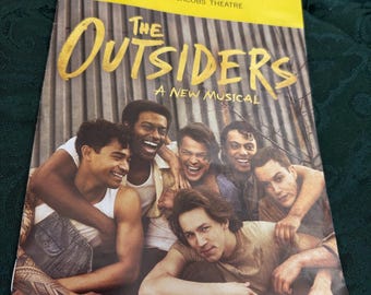 May include: Playbill for the musical "The Outsiders: A New Musical" at the Bernard B. Jacobs Theatre. The playbill features a photo of five young men, all smiling and looking at the camera.