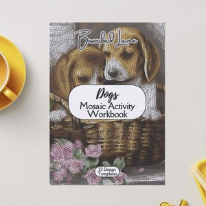 Op de afbeelding: Een "Dogs" mozaïek activiteit werkboek met een mozaïek afbeelding van twee honden in een mand. De cover heeft de tekst "Bowerbird Lane" en "Dogs Mosaic Activity Workbook". Het werkboek bevat 23 ontwerp sjablonen. Een gele kop en schotel staan links.