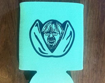 May include: A light teal can cooler featuring a black graphic of a man's face with glasses and a beard. The cooler is made of a textured material and has a cutout at the bottom.